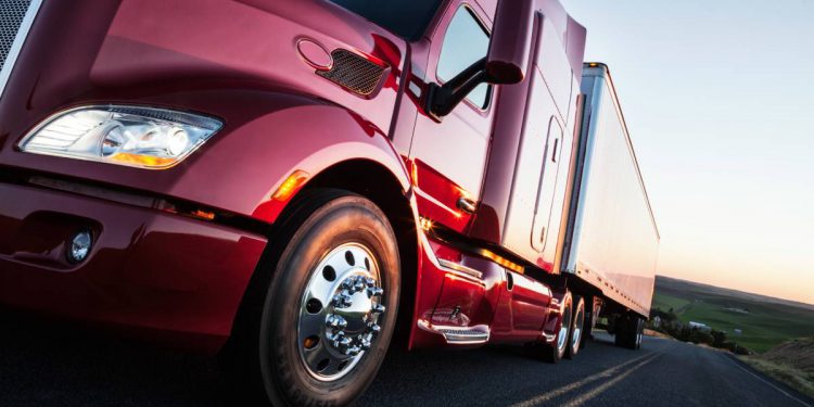 Front to rear low angle view of the cab of a commercial truck on the highway late in the day.